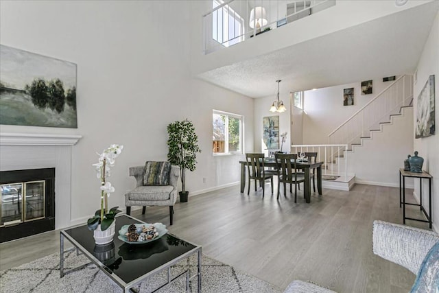 living room with an inviting chandelier, hardwood / wood-style floors, and a towering ceiling