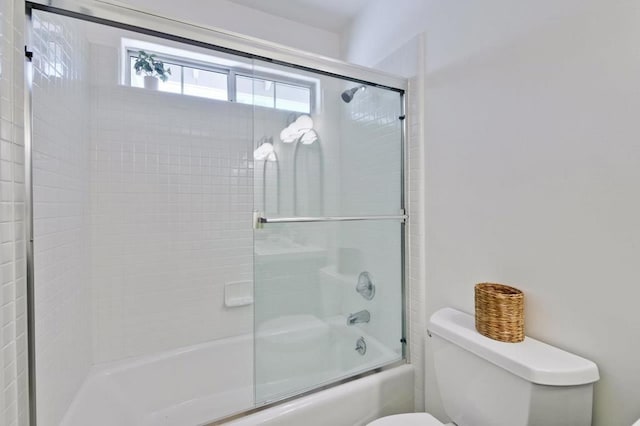 bathroom featuring toilet and combined bath / shower with glass door