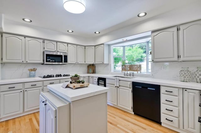 kitchen featuring a kitchen island, sink, light hardwood / wood-style flooring, and black appliances