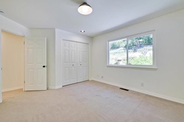 unfurnished bedroom featuring light colored carpet and a closet