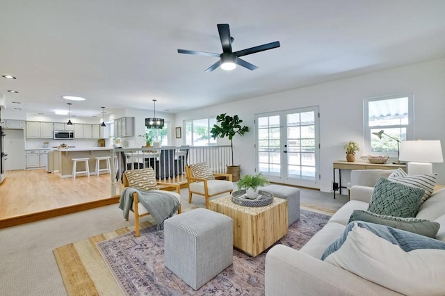 living room featuring french doors, ceiling fan, and light colored carpet