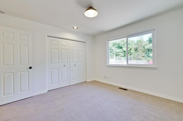 unfurnished bedroom featuring light colored carpet and a closet