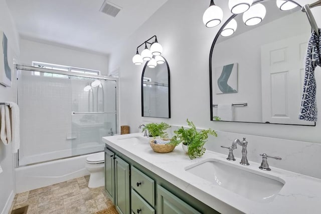 full bathroom with enclosed tub / shower combo, vanity, and toilet