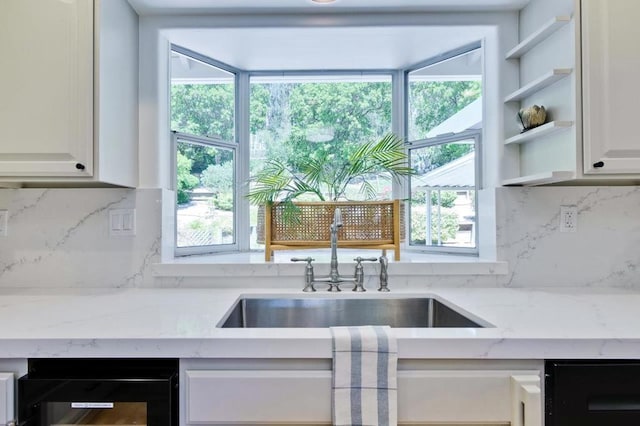 kitchen featuring sink, white cabinetry, a healthy amount of sunlight, beverage cooler, and light stone countertops