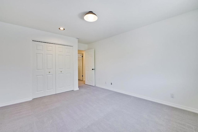 unfurnished bedroom with light carpet and a closet