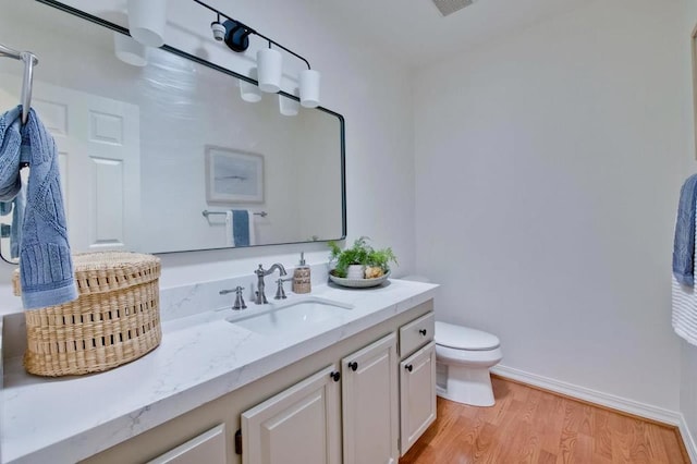 bathroom featuring wood-type flooring, toilet, and vanity