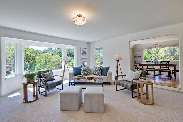 living room with an inviting chandelier, carpet floors, and a healthy amount of sunlight