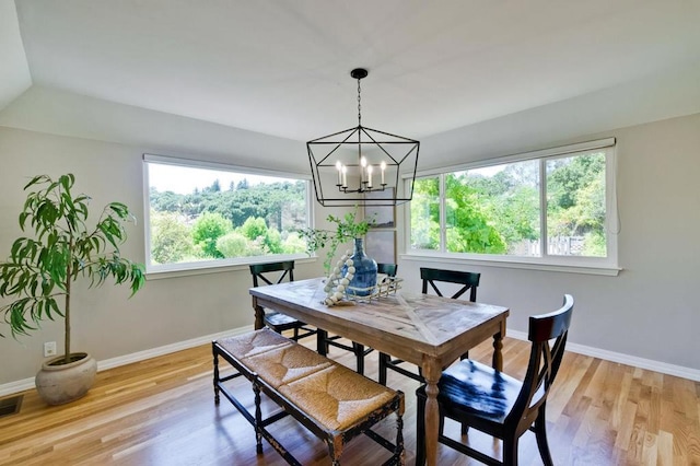 dining area featuring a healthy amount of sunlight, an inviting chandelier, and light hardwood / wood-style flooring