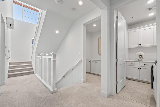 corridor featuring an AC wall unit, a skylight, light carpet, and washer / dryer