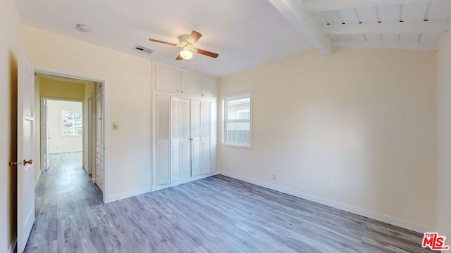 unfurnished bedroom with lofted ceiling with beams, ceiling fan, hardwood / wood-style floors, and a closet