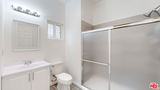 bathroom with an enclosed shower, vanity, hardwood / wood-style floors, and toilet