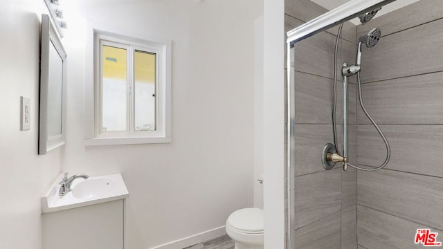 bathroom featuring vanity, tiled shower, and toilet