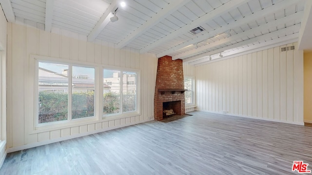 unfurnished living room with hardwood / wood-style flooring, track lighting, a fireplace, and beamed ceiling