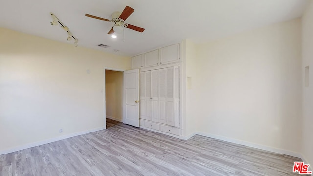 unfurnished bedroom with track lighting, ceiling fan, and light hardwood / wood-style flooring