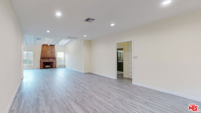 unfurnished living room featuring a brick fireplace and light wood-type flooring