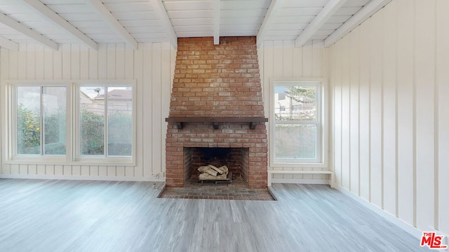 unfurnished living room with a brick fireplace, beamed ceiling, and light wood-type flooring