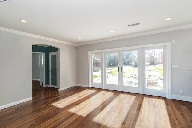 empty room with crown molding, dark wood-type flooring, and a healthy amount of sunlight