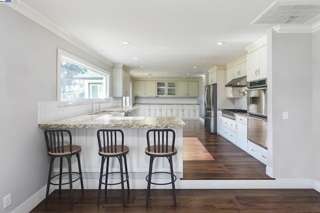 kitchen with appliances with stainless steel finishes, tasteful backsplash, sink, white cabinets, and kitchen peninsula