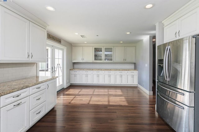 kitchen with stainless steel fridge, light stone counters, white cabinets, dark hardwood / wood-style flooring, and decorative backsplash