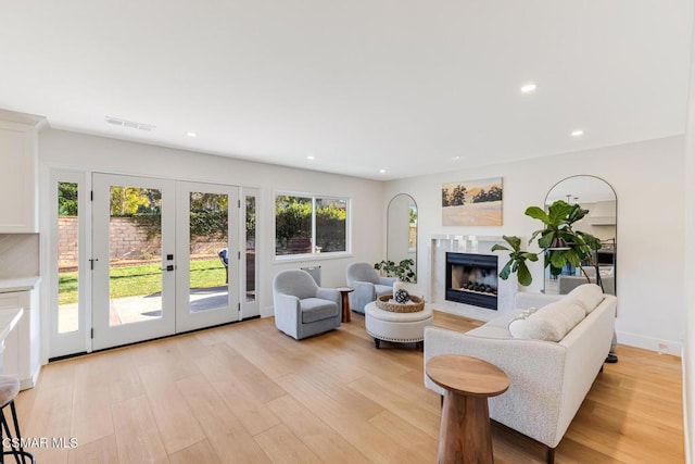 living room featuring french doors, a premium fireplace, and light hardwood / wood-style flooring