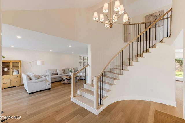 stairs featuring an inviting chandelier, a towering ceiling, and wood-type flooring