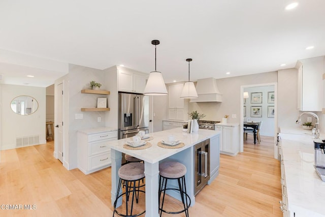 kitchen with a center island, high quality fridge, pendant lighting, light stone countertops, and white cabinets