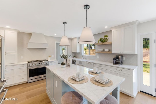 kitchen with stainless steel appliances, white cabinetry, custom range hood, and light stone counters