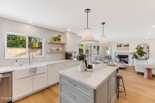 kitchen with white cabinetry, dishwasher, sink, and a kitchen island