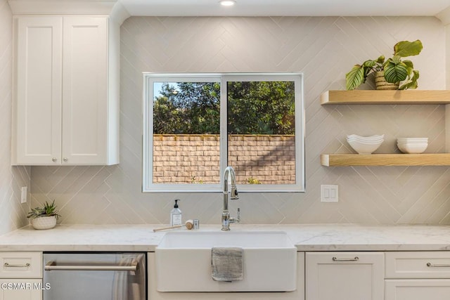 kitchen with white cabinetry, sink, light stone counters, and decorative backsplash