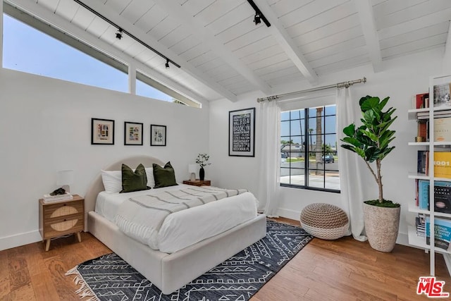 bedroom featuring hardwood / wood-style flooring, wooden ceiling, rail lighting, and vaulted ceiling with beams