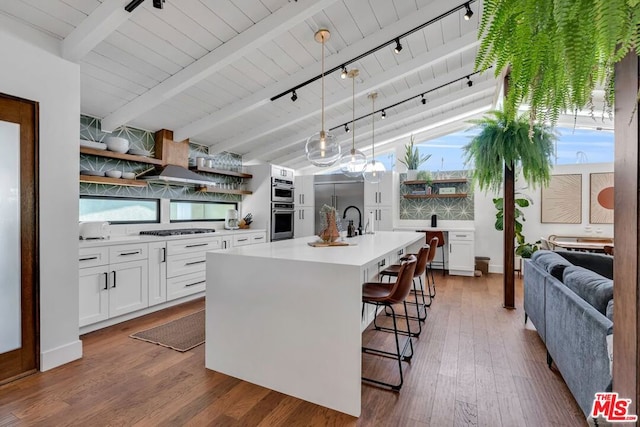 kitchen featuring pendant lighting, a center island with sink, white cabinets, and appliances with stainless steel finishes