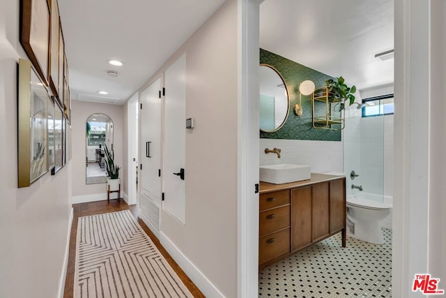 hallway with tile walls and sink