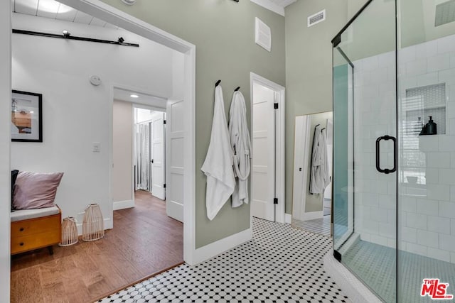 bathroom with an enclosed shower, hardwood / wood-style floors, and a high ceiling