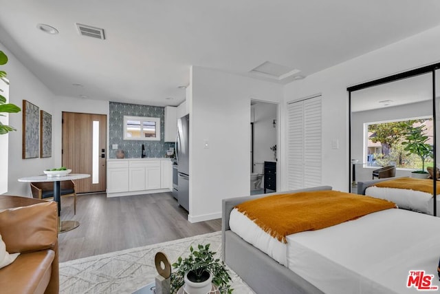 bedroom with stainless steel refrigerator, sink, and light hardwood / wood-style floors