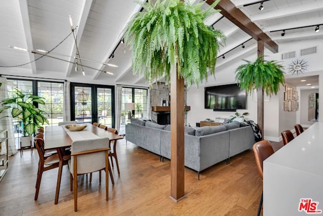 interior space featuring lofted ceiling with beams, rail lighting, french doors, and light hardwood / wood-style flooring