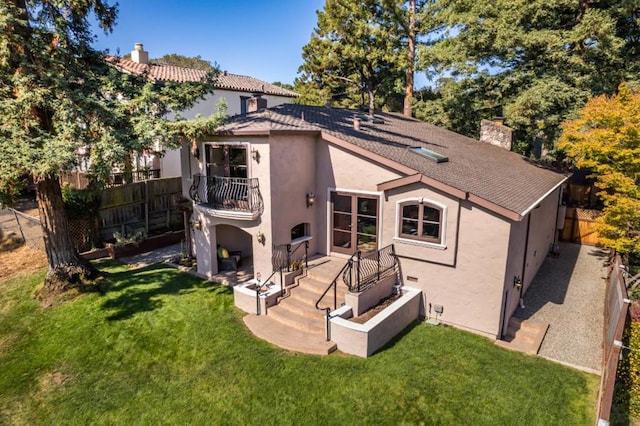 back of house featuring a lawn, a balcony, and a patio area