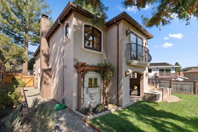 rear view of house featuring a balcony, a patio area, and a lawn