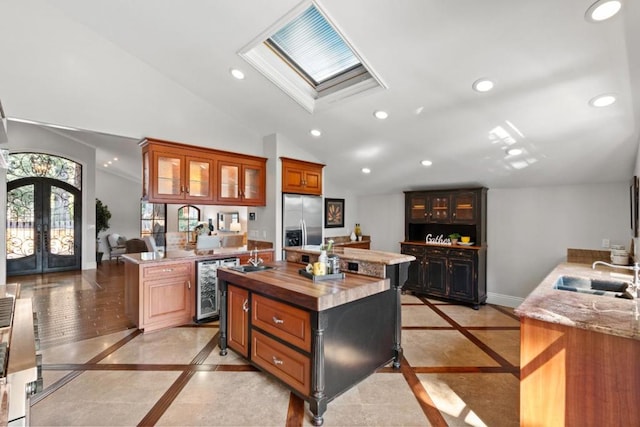 kitchen with stainless steel refrigerator with ice dispenser, a kitchen island, sink, and butcher block countertops