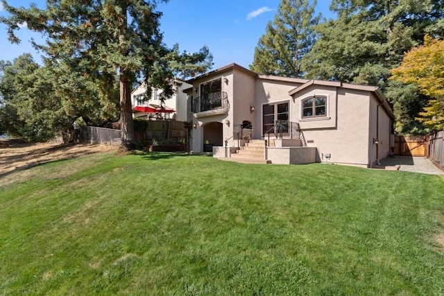 rear view of property with a balcony and a yard