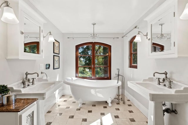 bathroom featuring dual sinks, a bathtub, and a chandelier