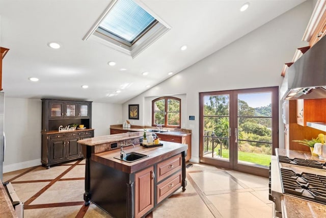 kitchen with sink, dark brown cabinets, lofted ceiling with skylight, and a kitchen island