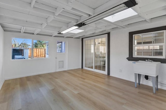 spare room featuring beam ceiling and light hardwood / wood-style flooring