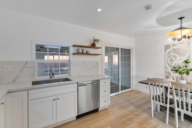 kitchen featuring pendant lighting, tasteful backsplash, white cabinetry, dishwasher, and sink