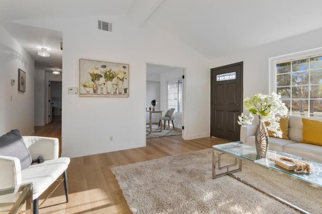 living room featuring vaulted ceiling with beams and light hardwood / wood-style floors