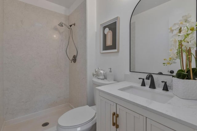 bathroom featuring vanity, toilet, and tiled shower