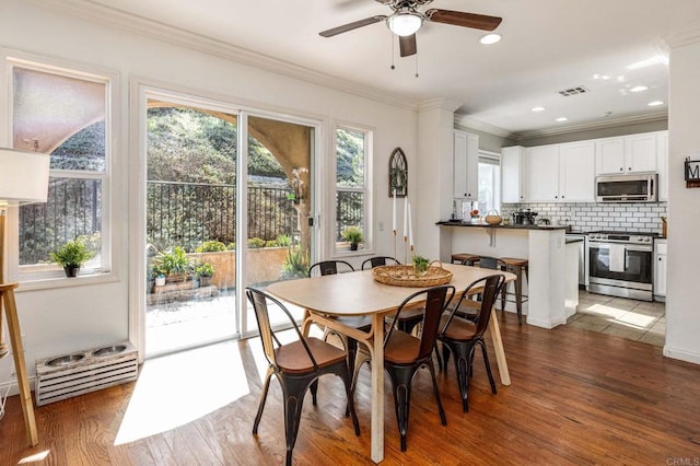 dining room with crown molding, ceiling fan, and dark hardwood / wood-style flooring