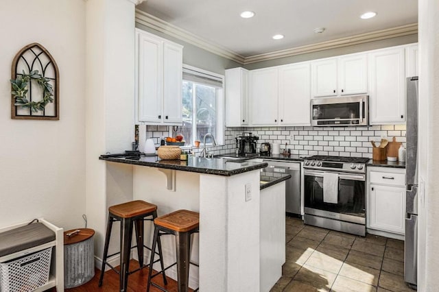 kitchen featuring appliances with stainless steel finishes, a breakfast bar, tasteful backsplash, sink, and white cabinets