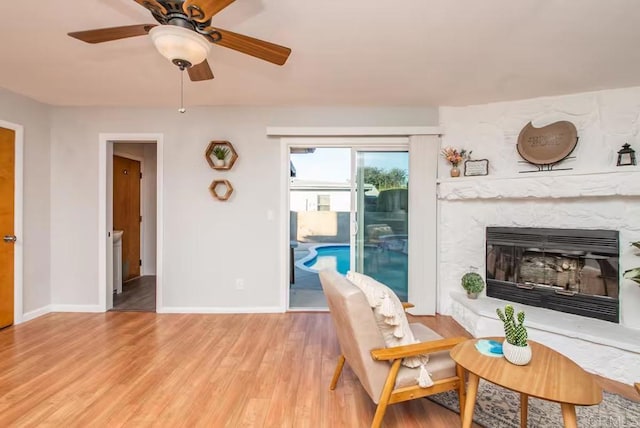 interior space featuring ceiling fan, a fireplace, and light hardwood / wood-style floors