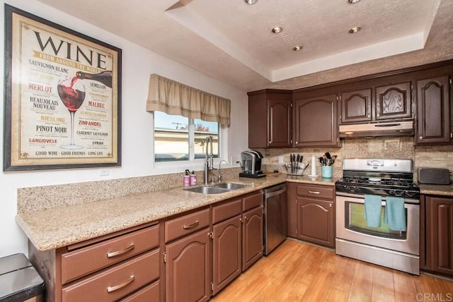 kitchen with a raised ceiling, tasteful backsplash, sink, stainless steel appliances, and light wood-type flooring