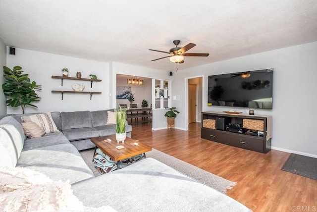 living room featuring wood-type flooring and ceiling fan with notable chandelier